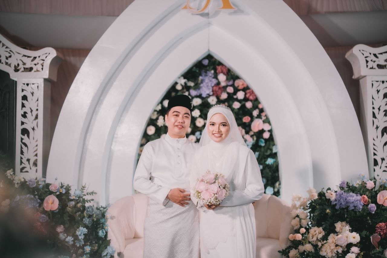 Afiqah dan Firdaus berpakaian putih di pelamin berbunga di Assolihin