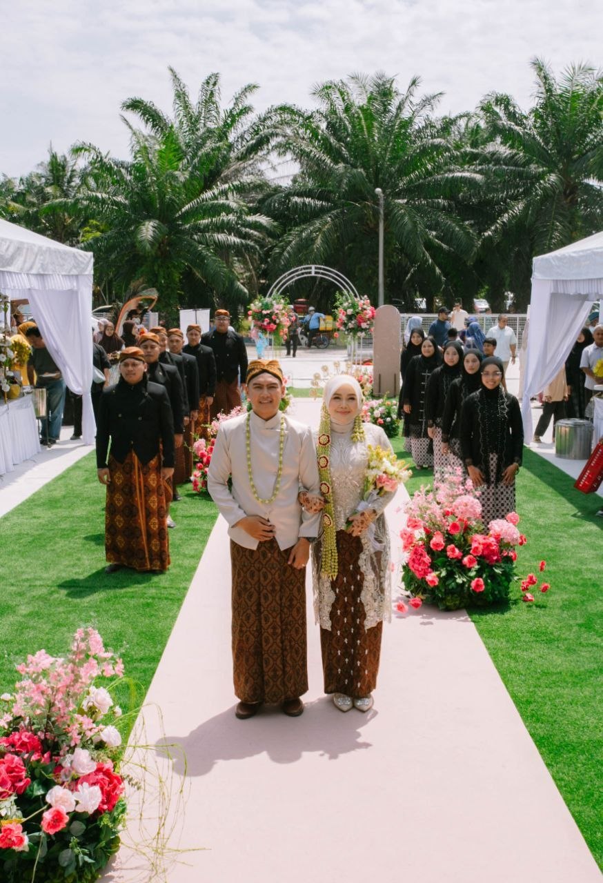 Julia dan Ikmal melalui laluan bunga di laman terbuka bersama tetamu