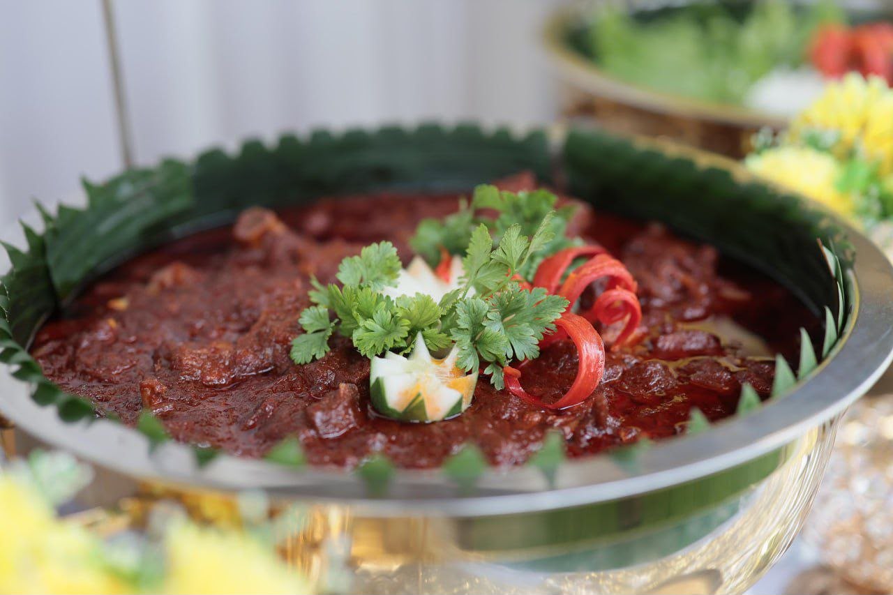 Close-up lauk utama berwarna merah dengan hiasan herba dan cili
