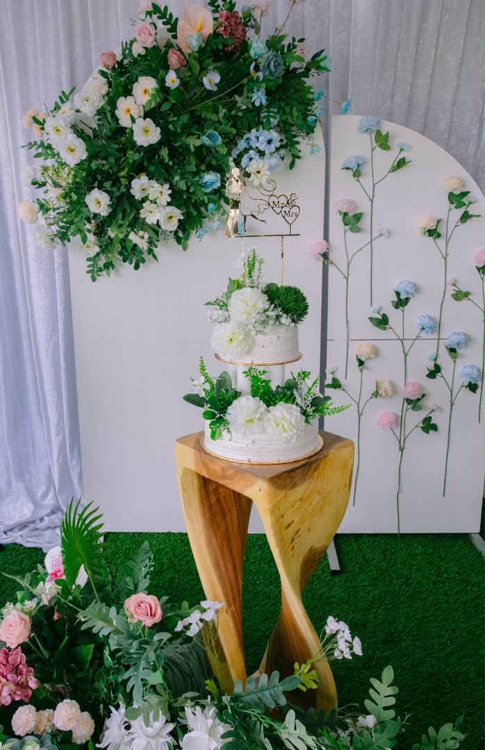 Kek pengantin putih dengan hiasan bunga pastel di ruang outdoor